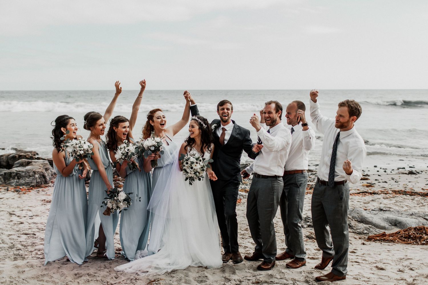 bridal party cheering on bride and groom at crystal cove beach