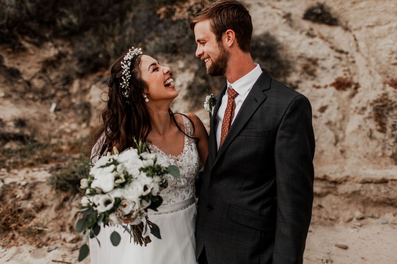 bride and groom looking at each other on beach backdrop