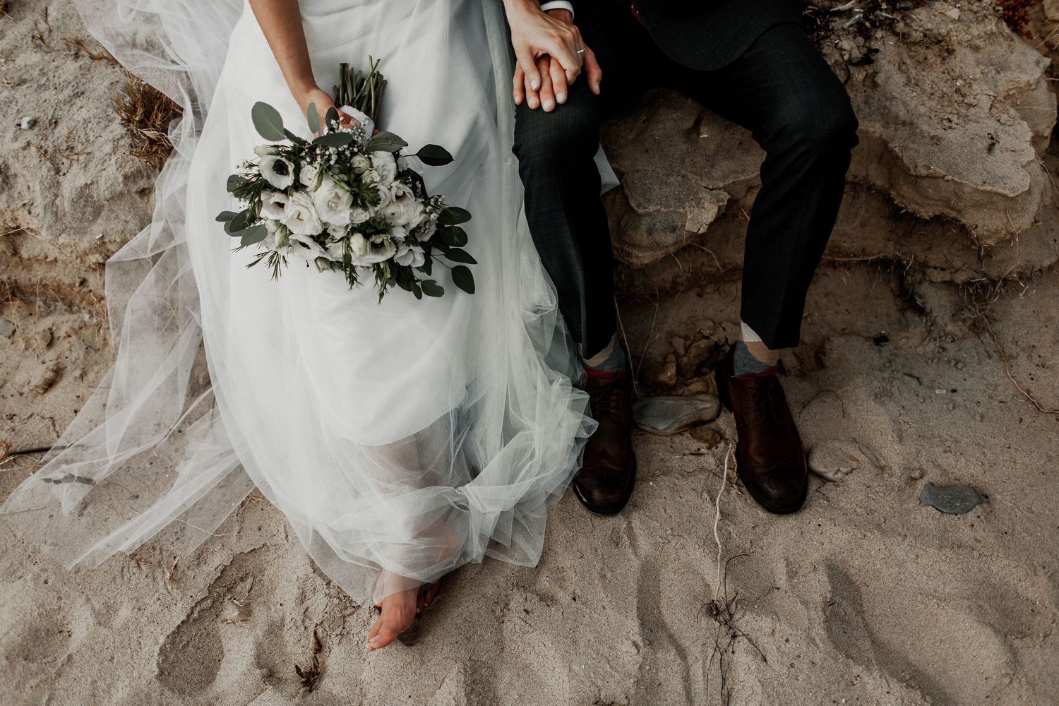 bride and groom sitting on a log with bouquet and details