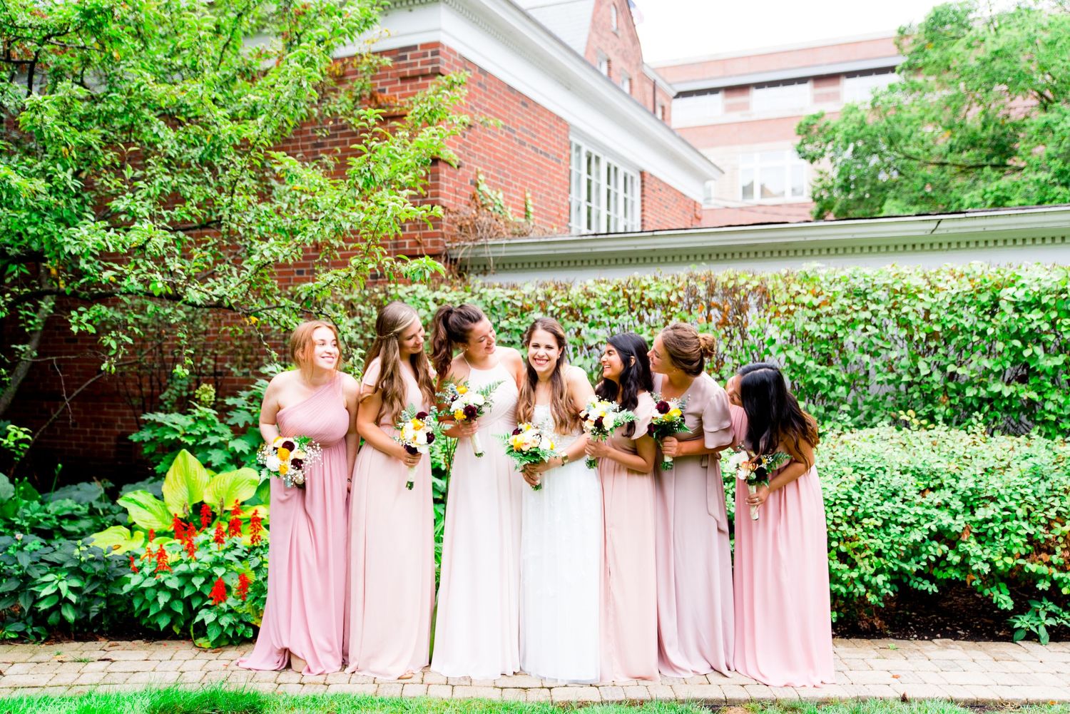 bridesmaids in pink dresses cheer for bride on her wedding day