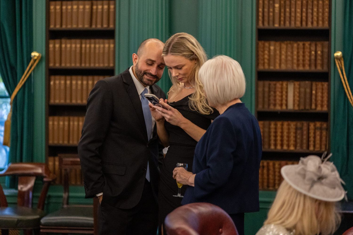 3 wedding guests reviewing photographs from the wedding ceremony on their phones. Stuart Morris Liverpool city wedding photographer.