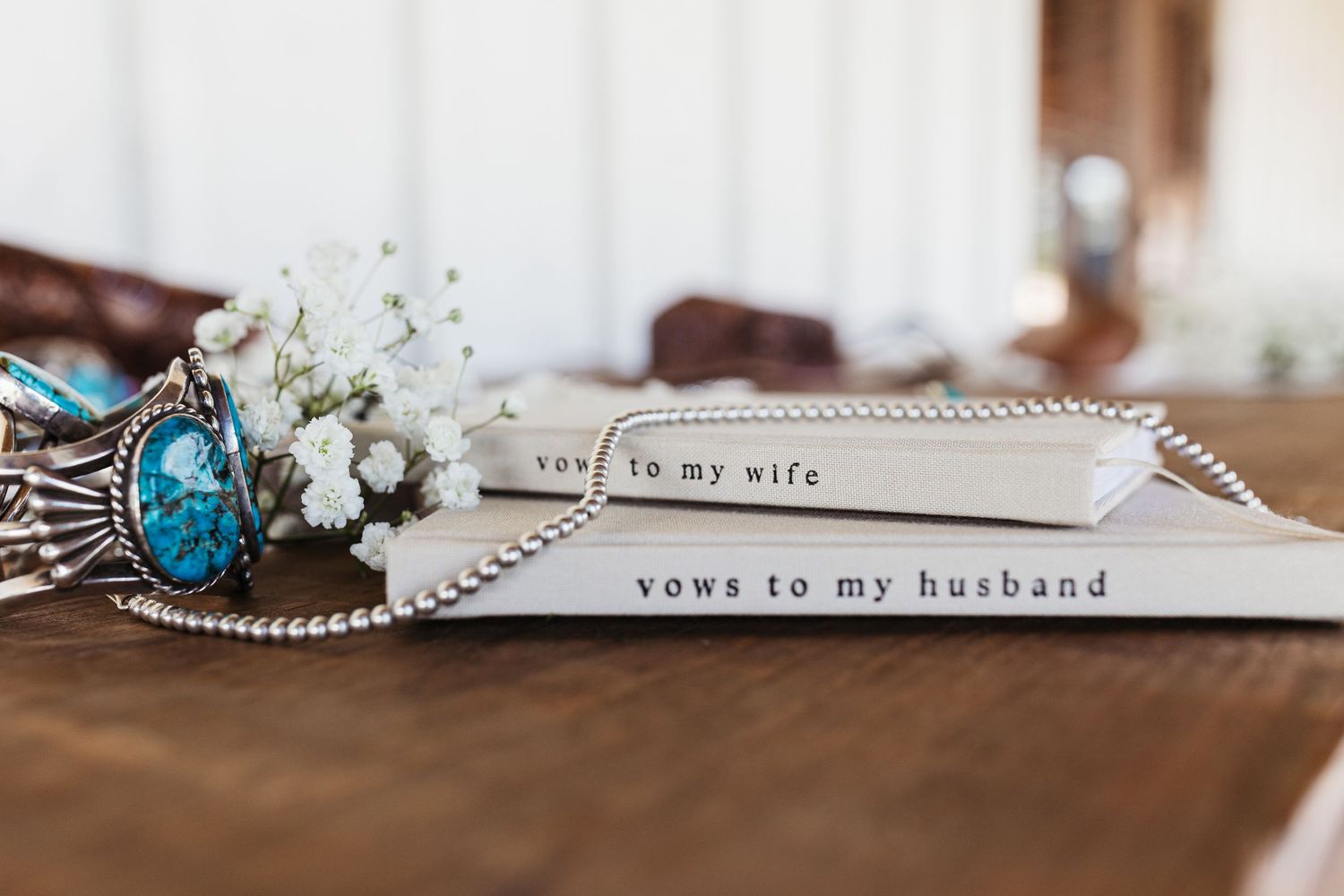 Silver "To my wife" and "Vows to my husband" wedding bands displayed with white floral decor and vintage rings.