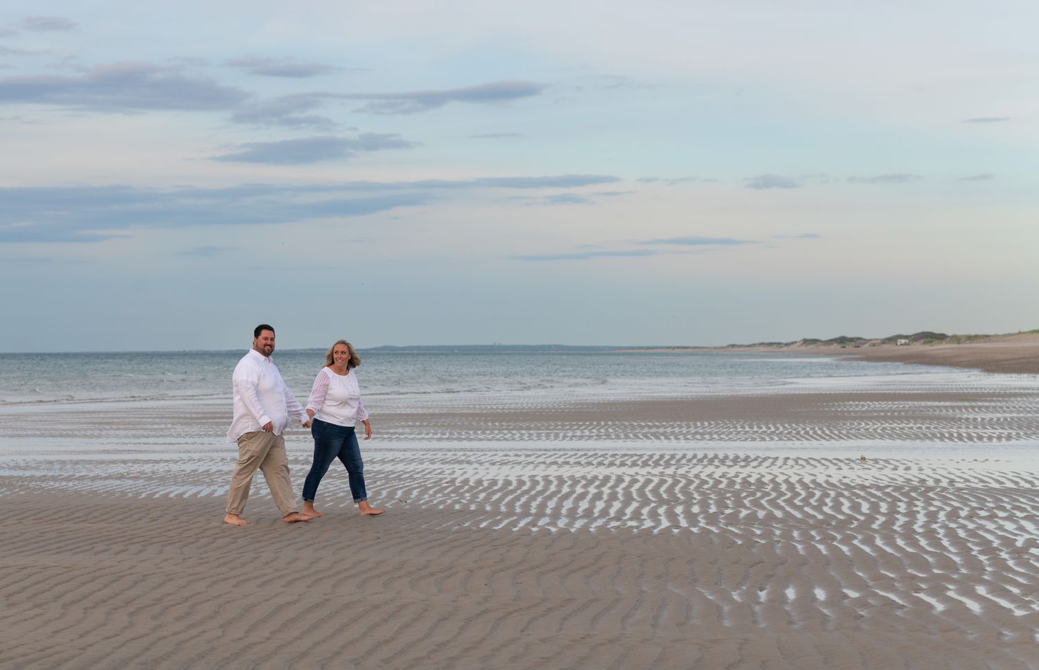 Couple walking at low tide on Sandy Neck Beach Park in Barnstable