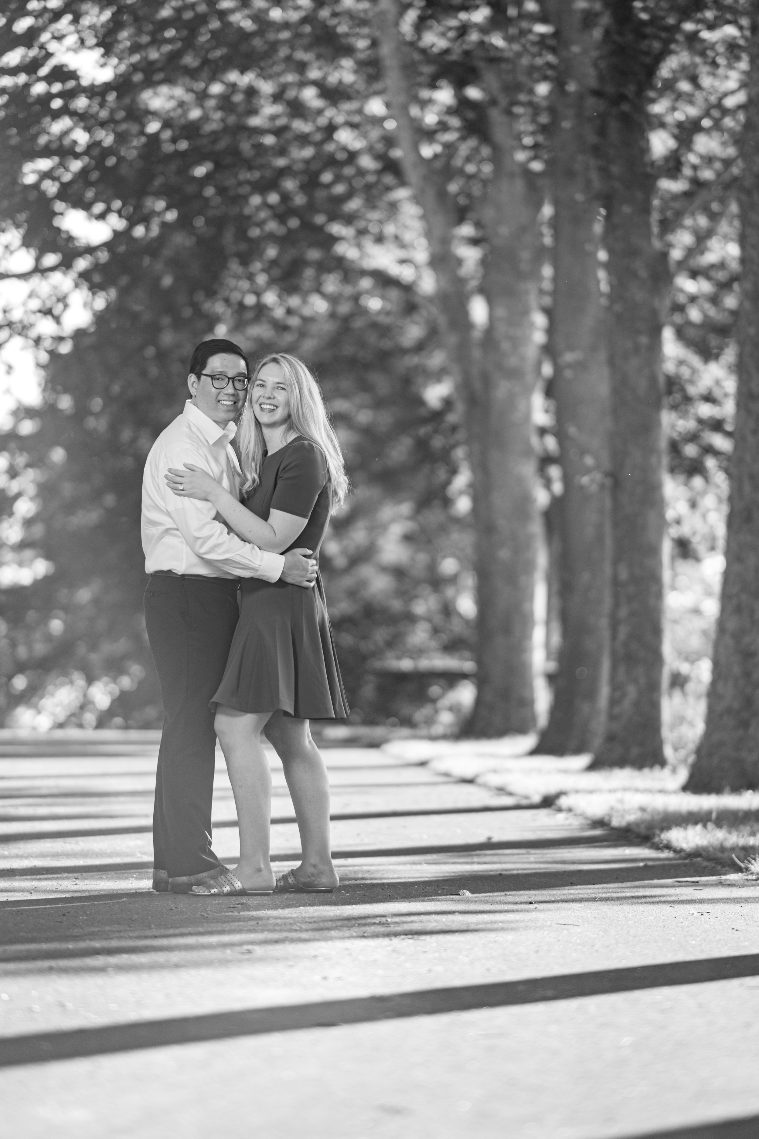 A couple shares a romantic moment in a tree-lined pathway, shown in three connecting black and white photos.