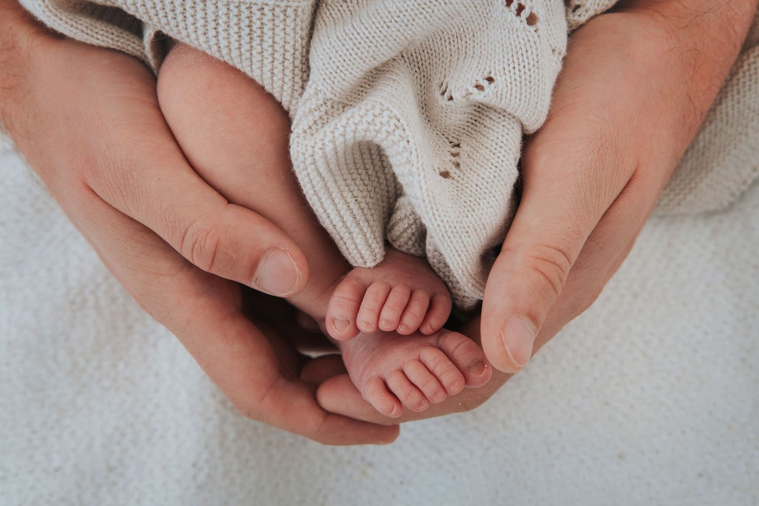 Newborn toes held by hands by devon photographer Melanie Barnfield