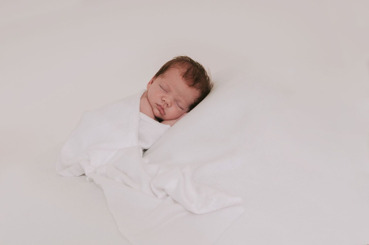 Simple and pure baby sleeping on white blanket by devon based photographer Melanie Barnfield