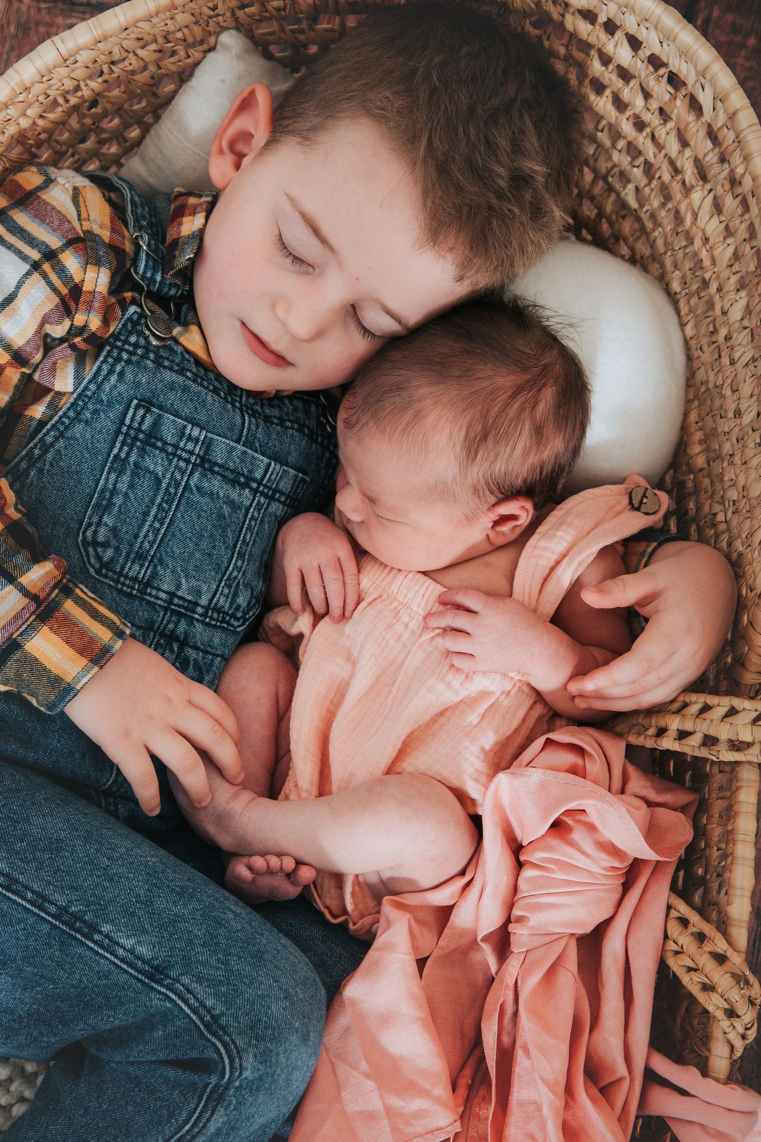Newborn baby held by sleeping big brother by devon based photographer Melanie Barnfield