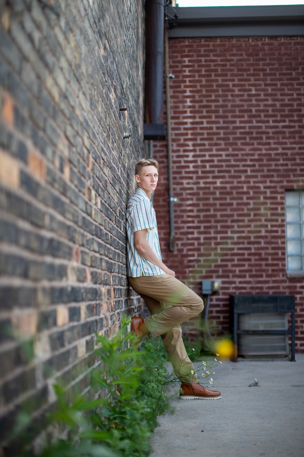 Person crouching against red brick wall with green foliage in multiple artistic urban shots.