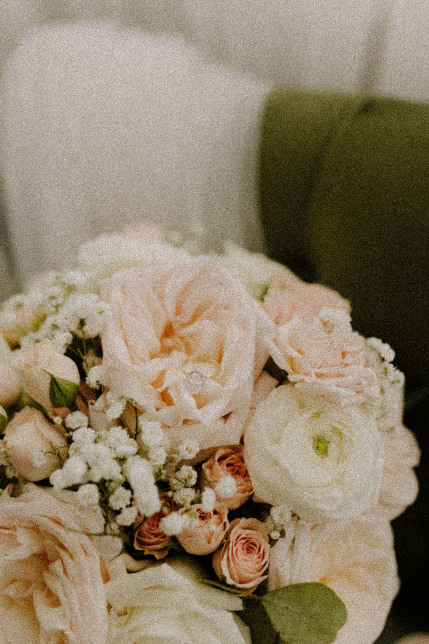 Delicate pink roses and white flowers arranged in a romantic wedding bouquet with soft blurred background.