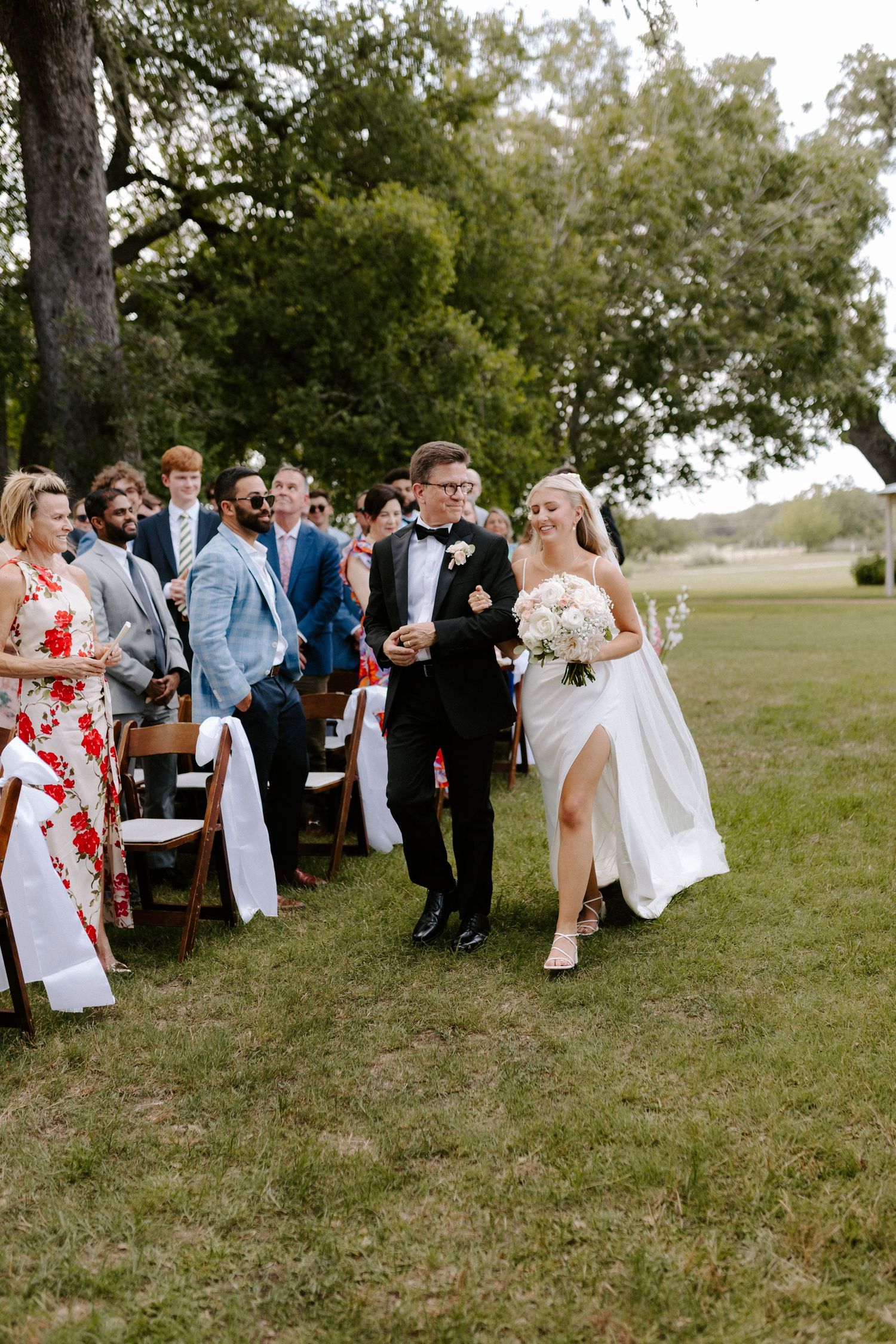 Wedding guests watch as couple walks down aisle during outdoor ceremony.