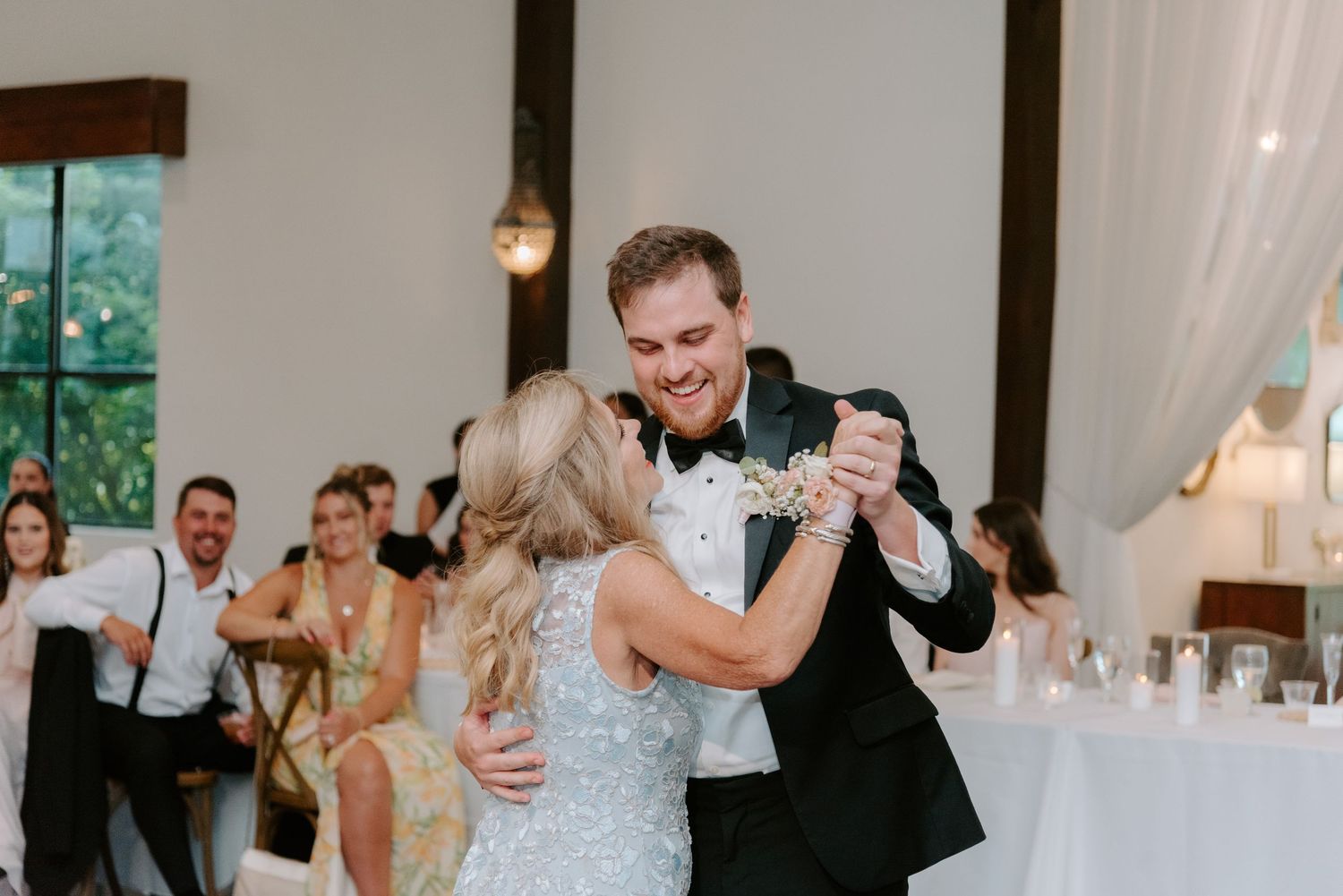 Dancing couples celebrate at an indoor wedding reception with elegant decor.