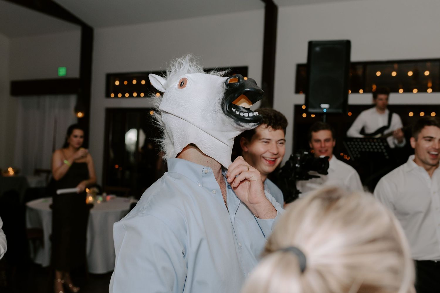 Wedding party guests dance wearing funny animal head masks during a reception celebration.