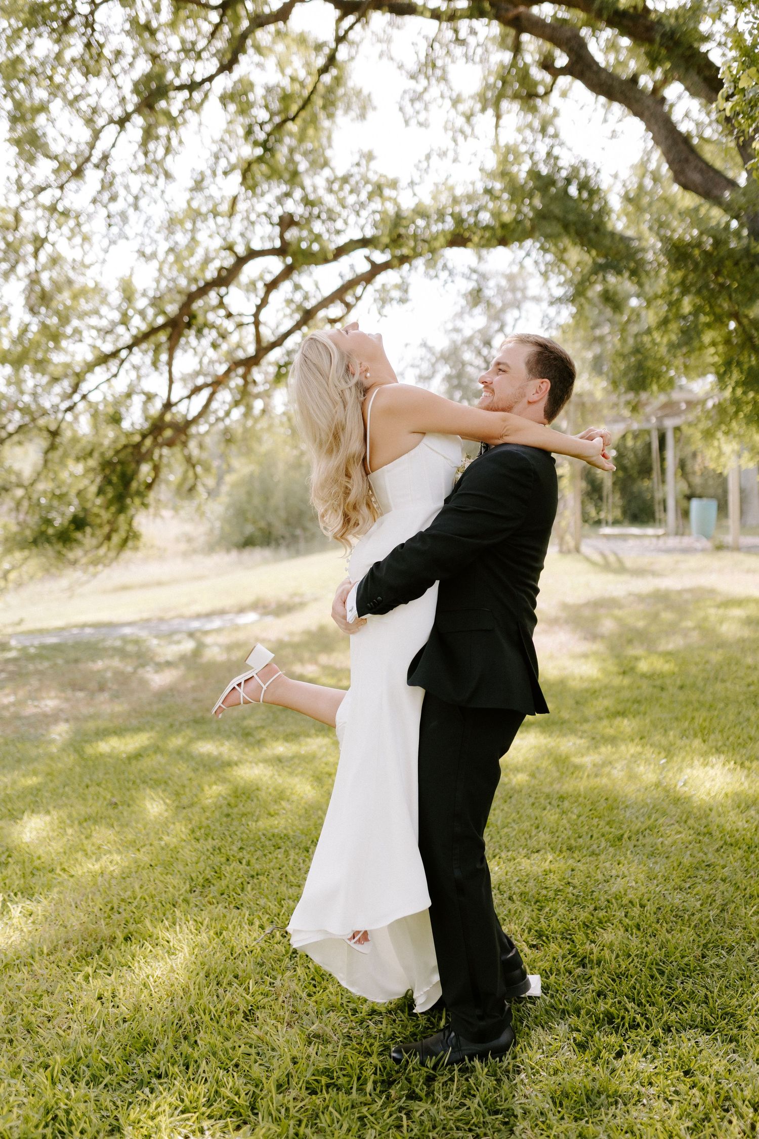 A romantic wedding moment captured as a couple embraces in a sunlit garden setting.