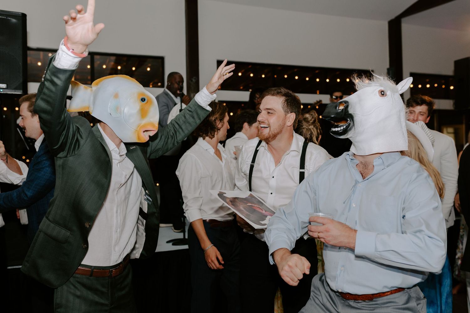 Wedding party guests dancing and celebrating while wearing playful animal masks.