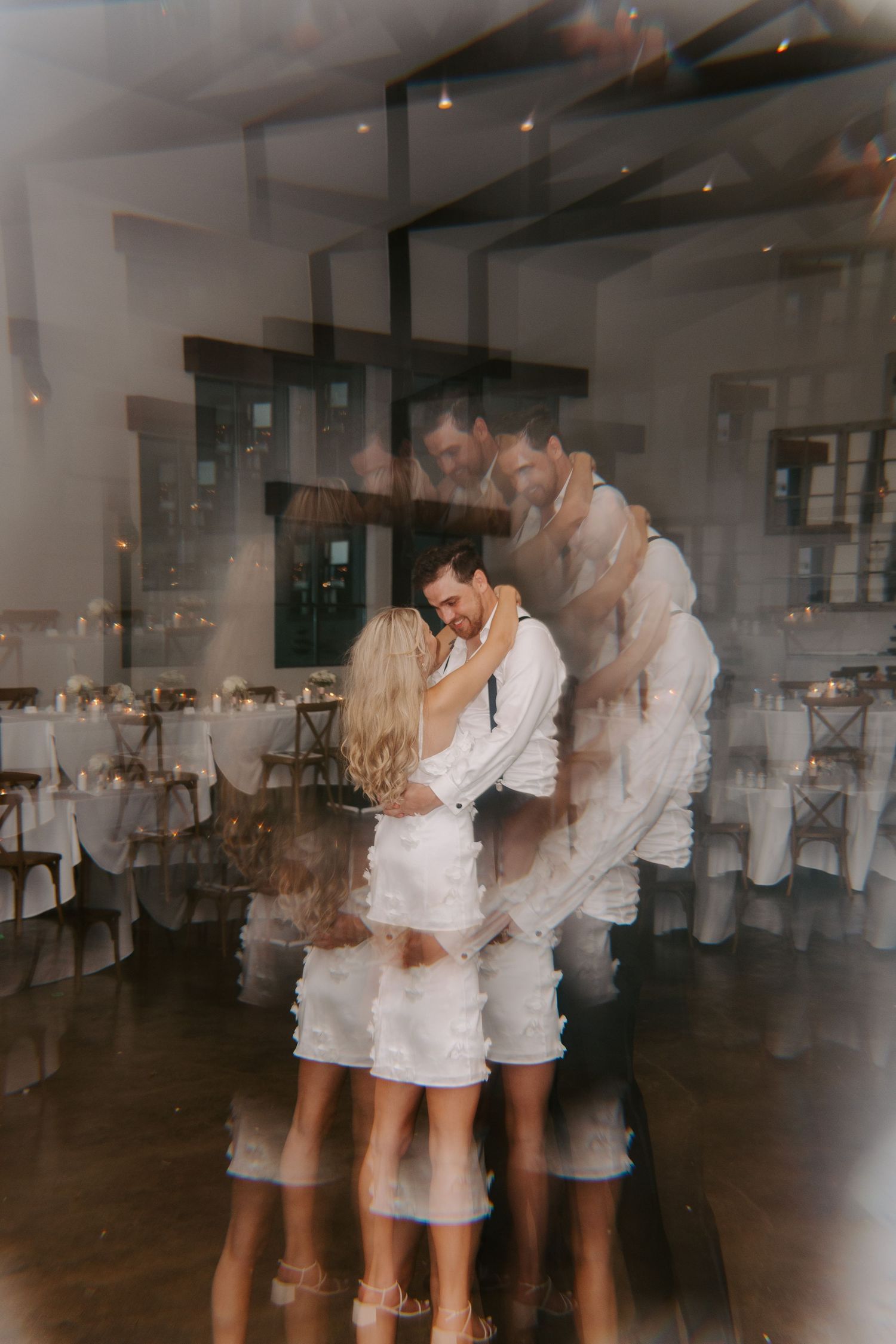 Artistic multiple exposure photo of couple dancing in white reception venue.