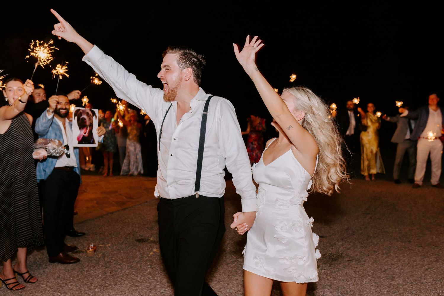 Newlyweds celebrating with sparklers during nighttime wedding exit.