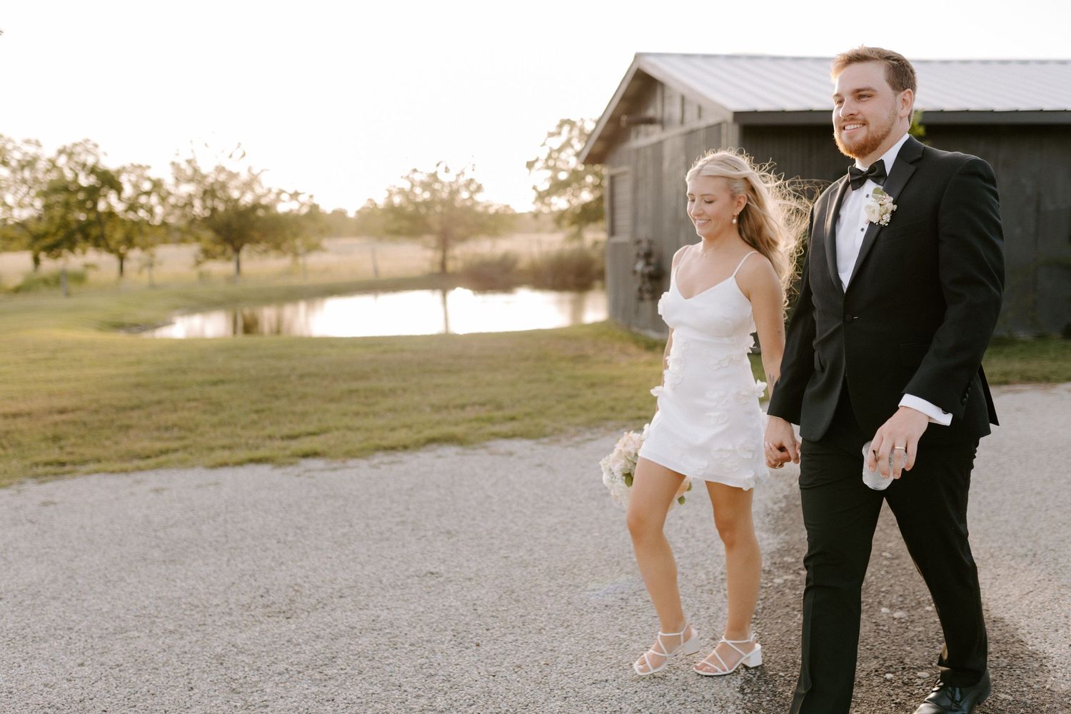 A couple walks together on a gravel pathway during sunset, creating a romantic silhouette against the golden sky.