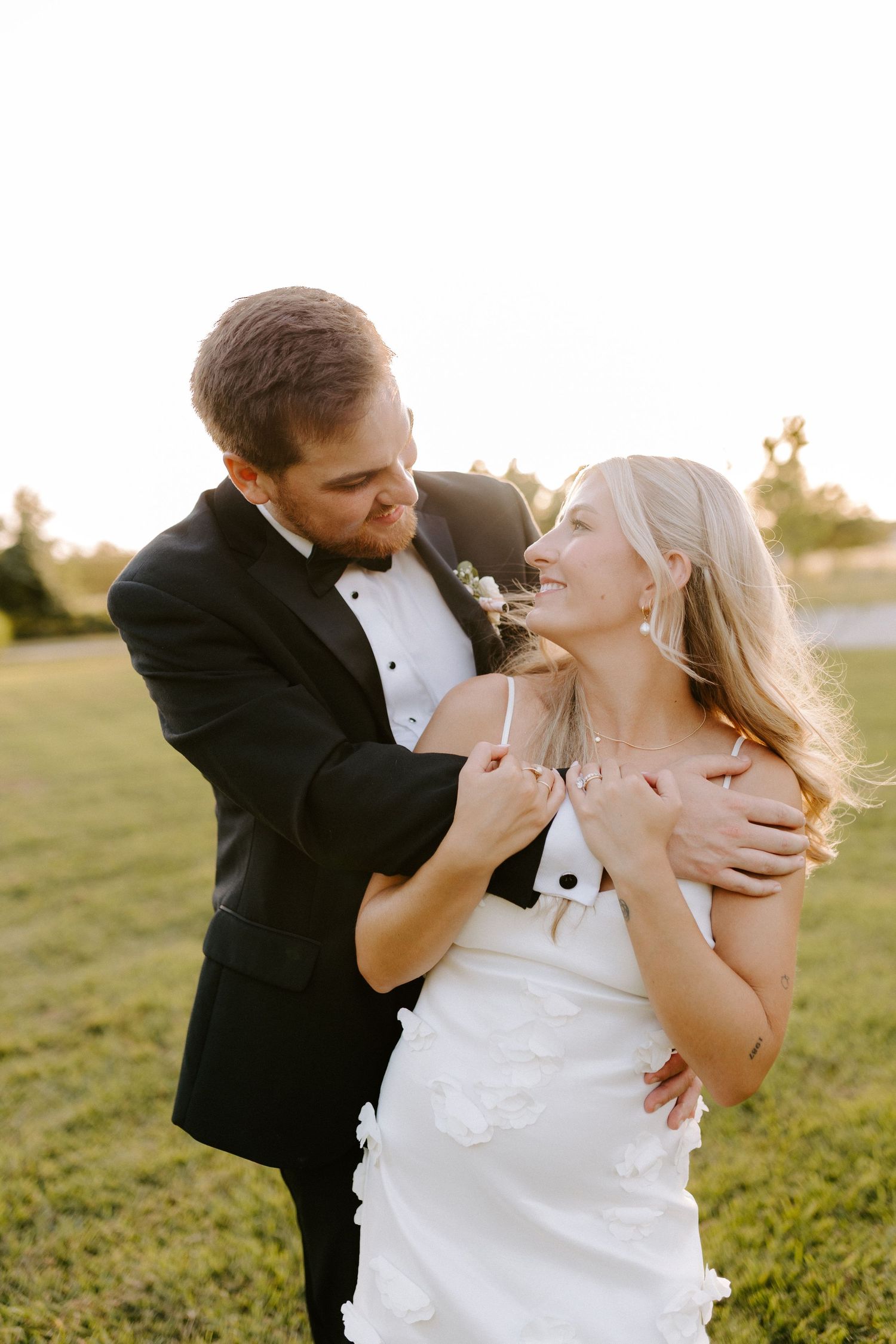 Romantic sunset portrait of newlyweds embracing in a sun-drenched field during their wedding celebration.