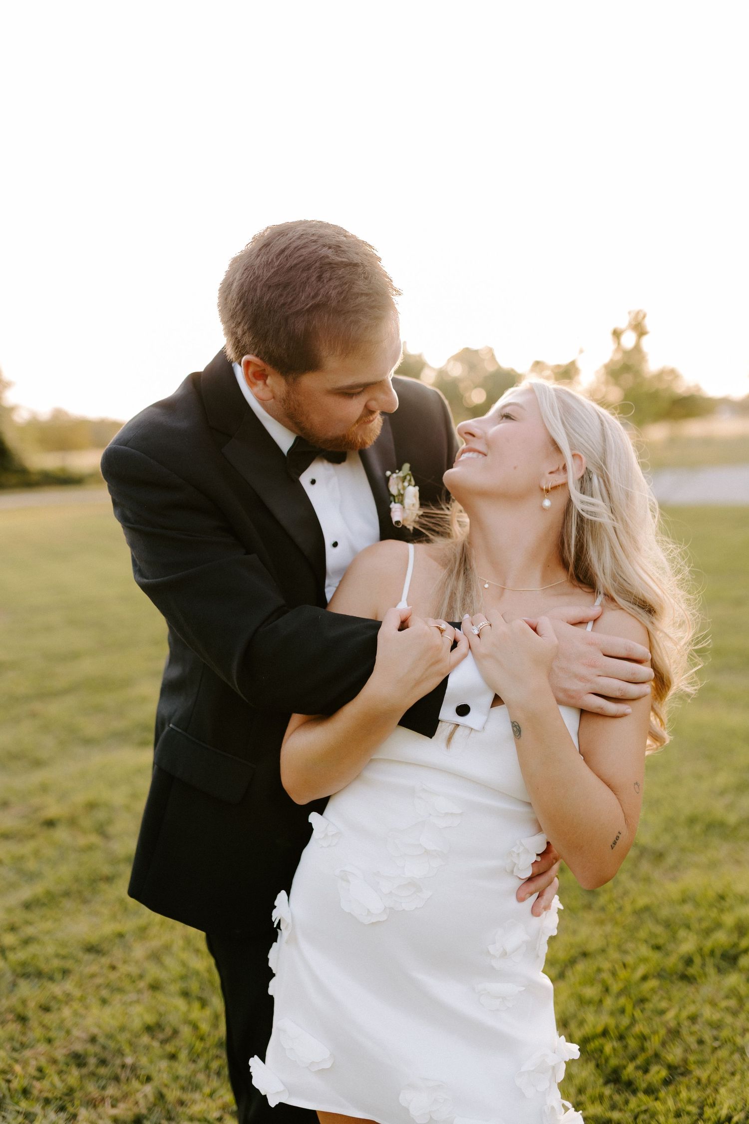 Joyful wedding couple shares an intimate moment outdoors during golden hour.