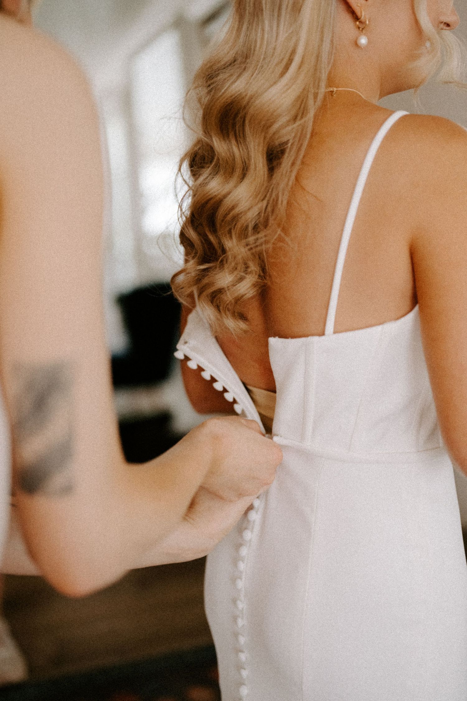 Close-up detail of a white wedding dress with delicate button closures and straps.