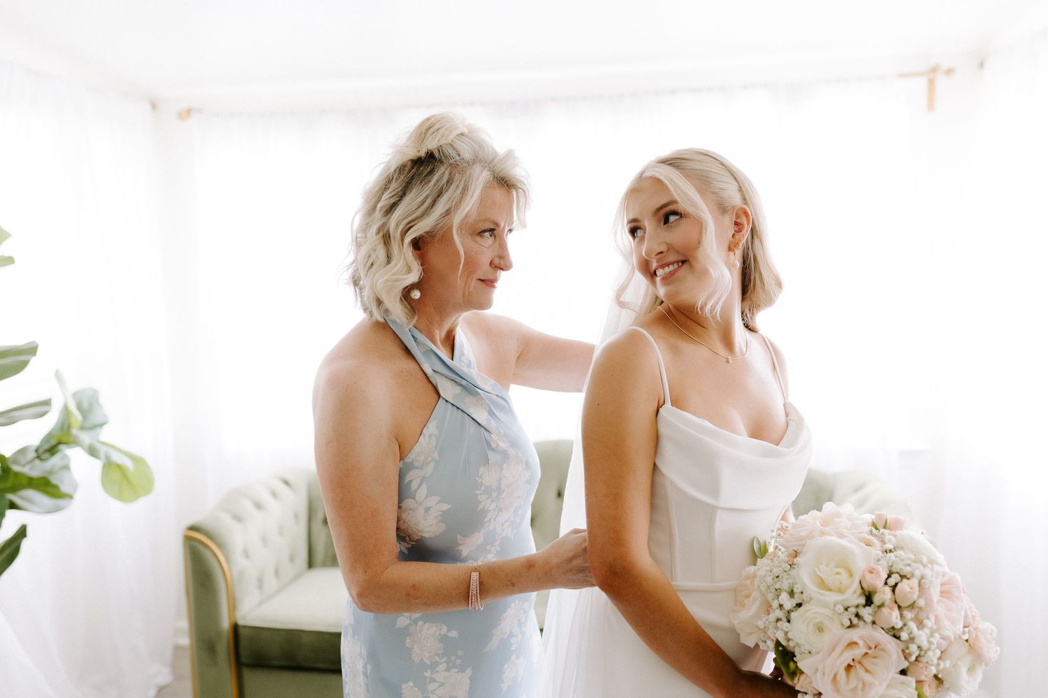 Tender moment shared during wedding preparations in a light-filled room.