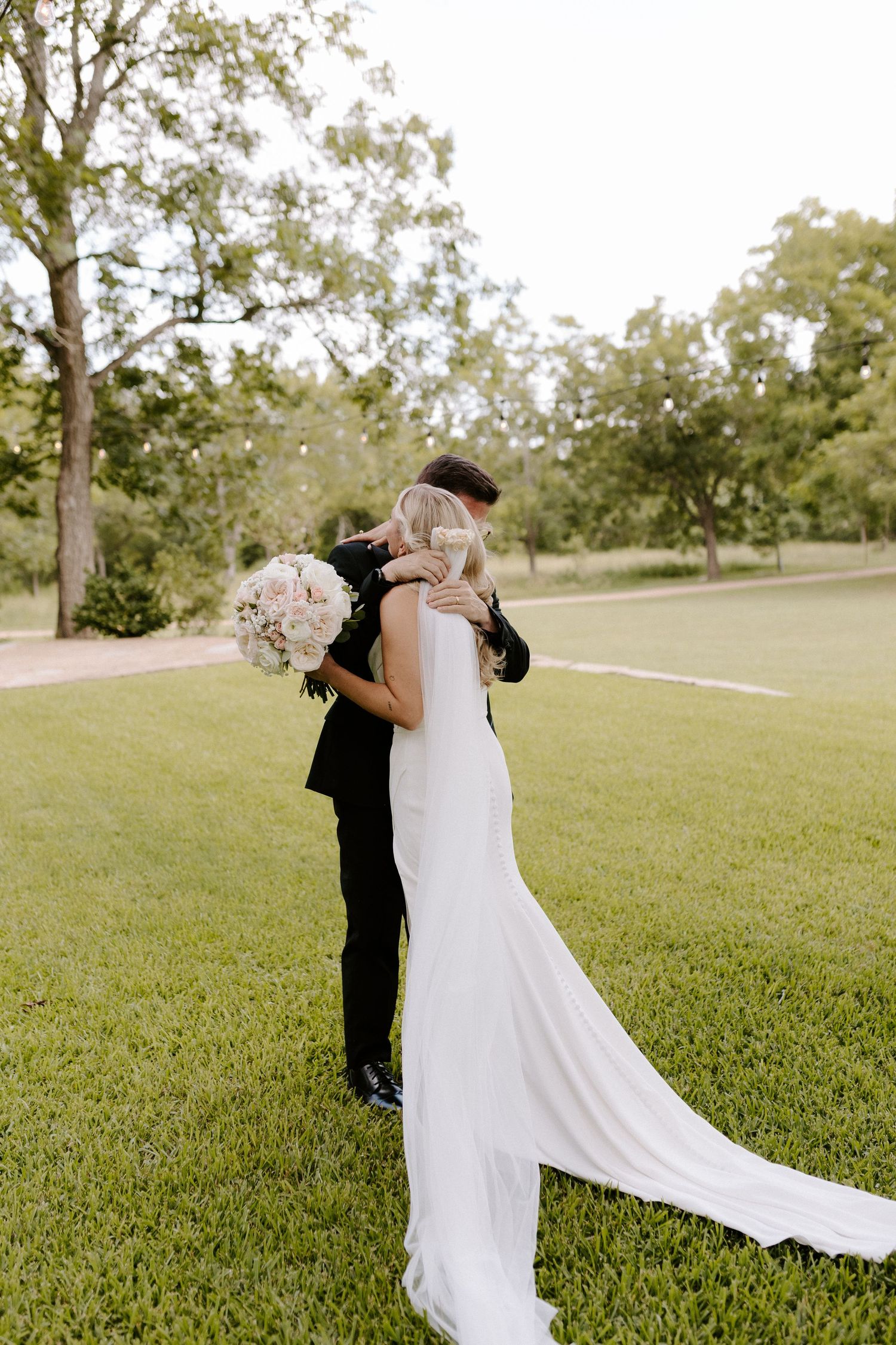 A romantic first look moment captured between couple on grassy lawn during outdoor wedding celebration.
