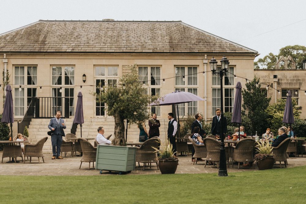 Exterior views of a classic stone building with manicured lawn and outdoor seating areas lined up along the patio.