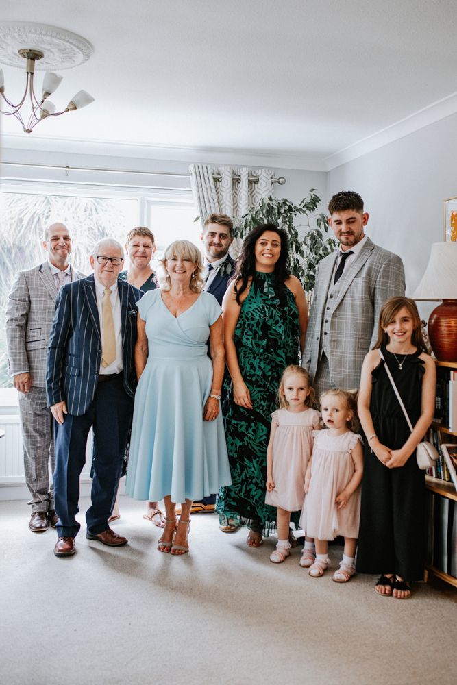 Group photo of family members dressed up for a special occasion gathered together in a bright living room interior.