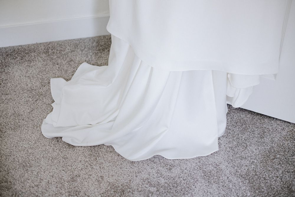 The bottom hem of a flowing white wedding dress cascades across gray carpet in a series of connected detail shots.