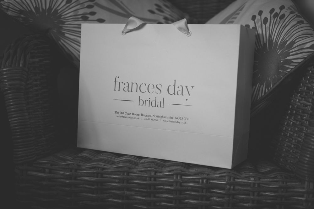 A black and white shopping bag with 'frances day' bridal text sits on a woven basket surface.