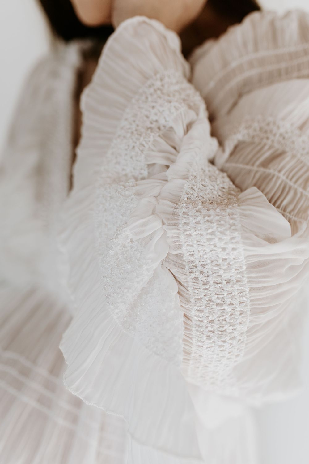 Close-up detail of delicate white lace and tulle fabric with ruffled texture creating an ethereal bridal fashion effect.