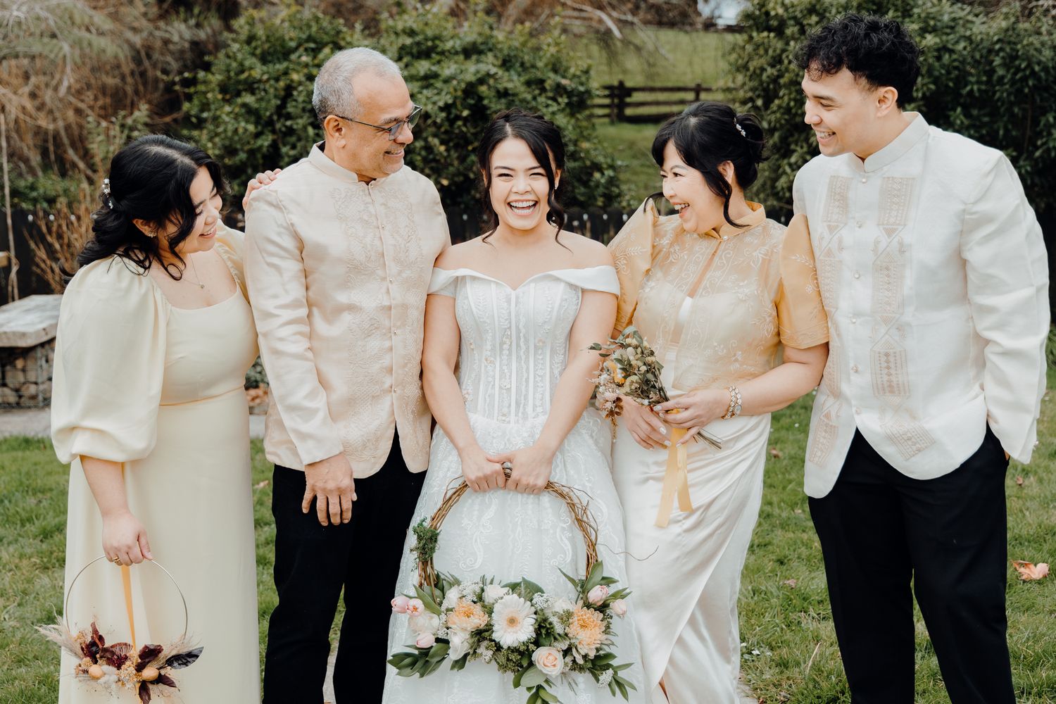 Wedding group photo with family members in cream and white formal attire.