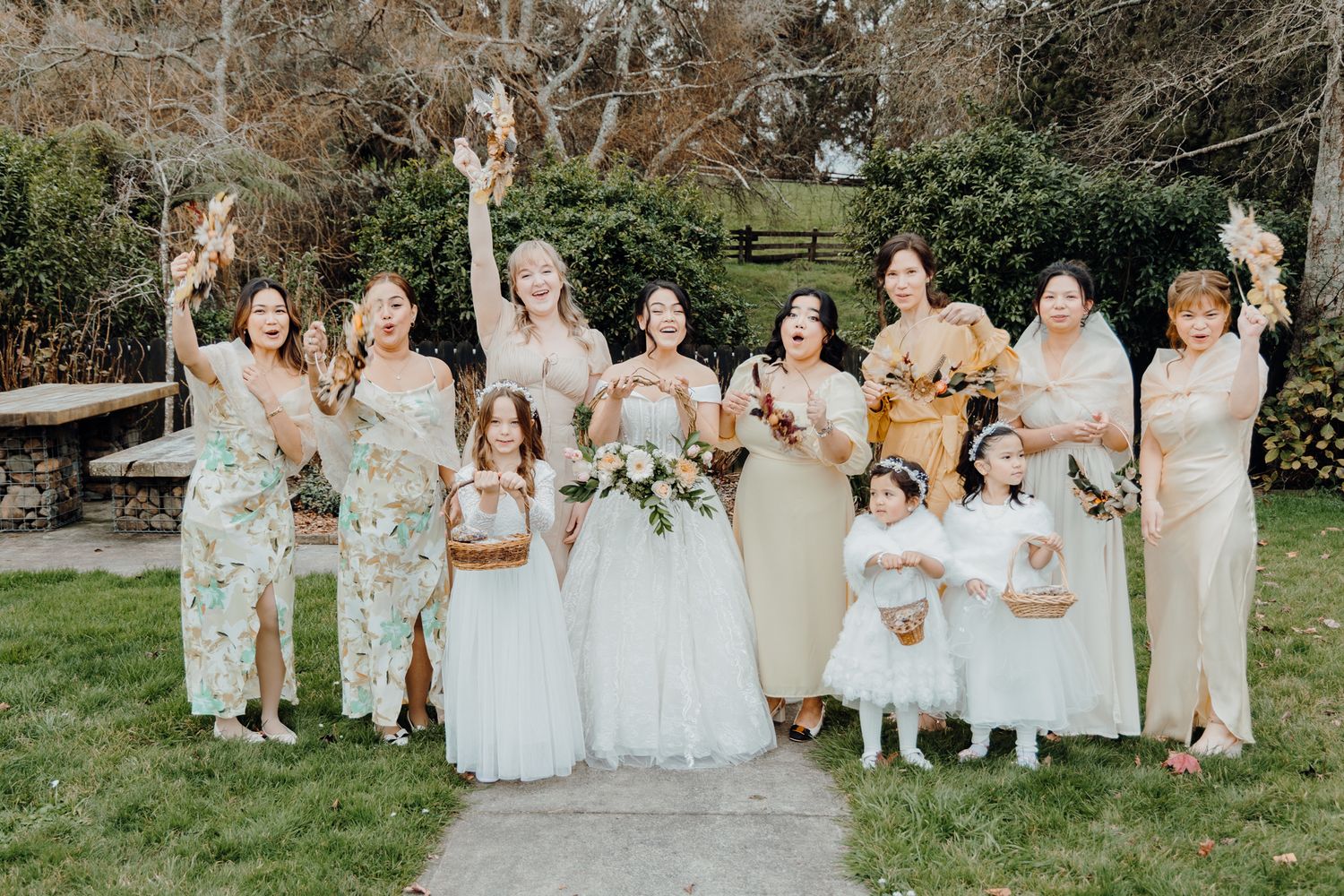 Wedding party in pastel and floral dresses posing together outdoors.