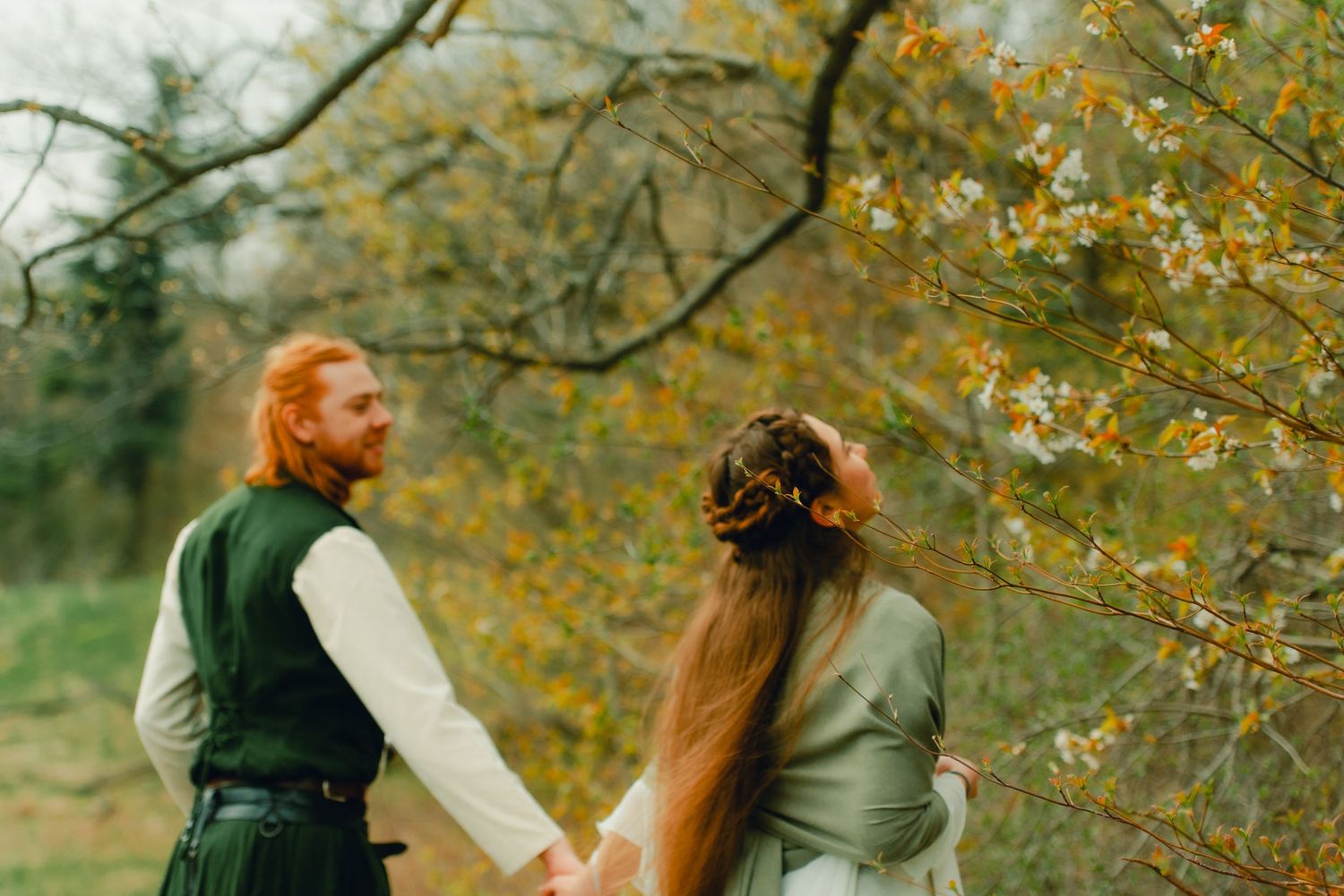 Couple walking into spring forest together, sniffing blossoms