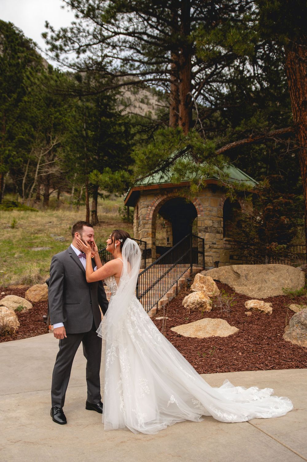 A romantic wedding couple sharing a moment outside a rustic stone gazebo.