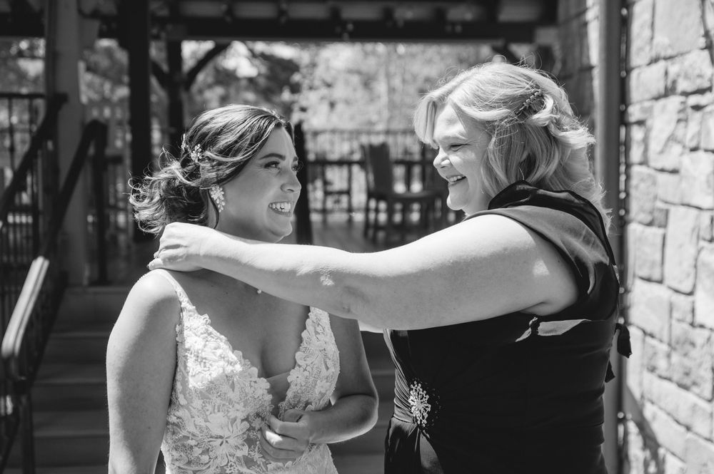 Two people share an emotional black and white moment on a covered patio beside a stone wall.