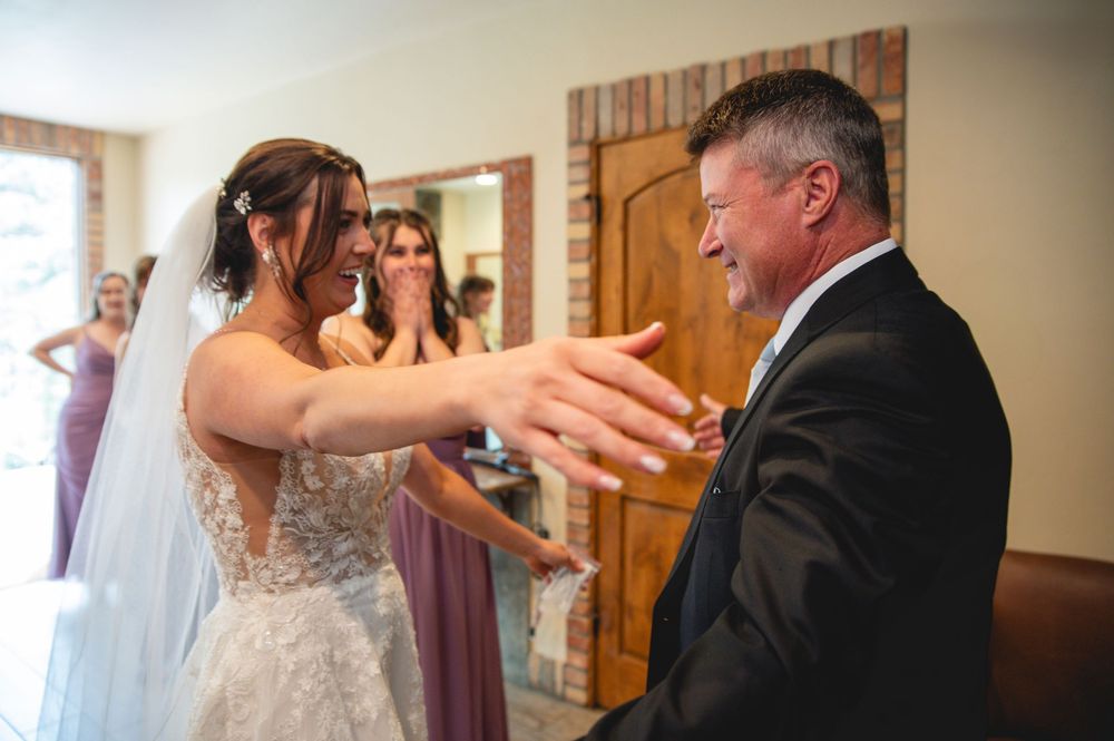 An emotional moment at a wedding ceremony shows a person in a bridal gown reaching out to hug someone in a dark suit.