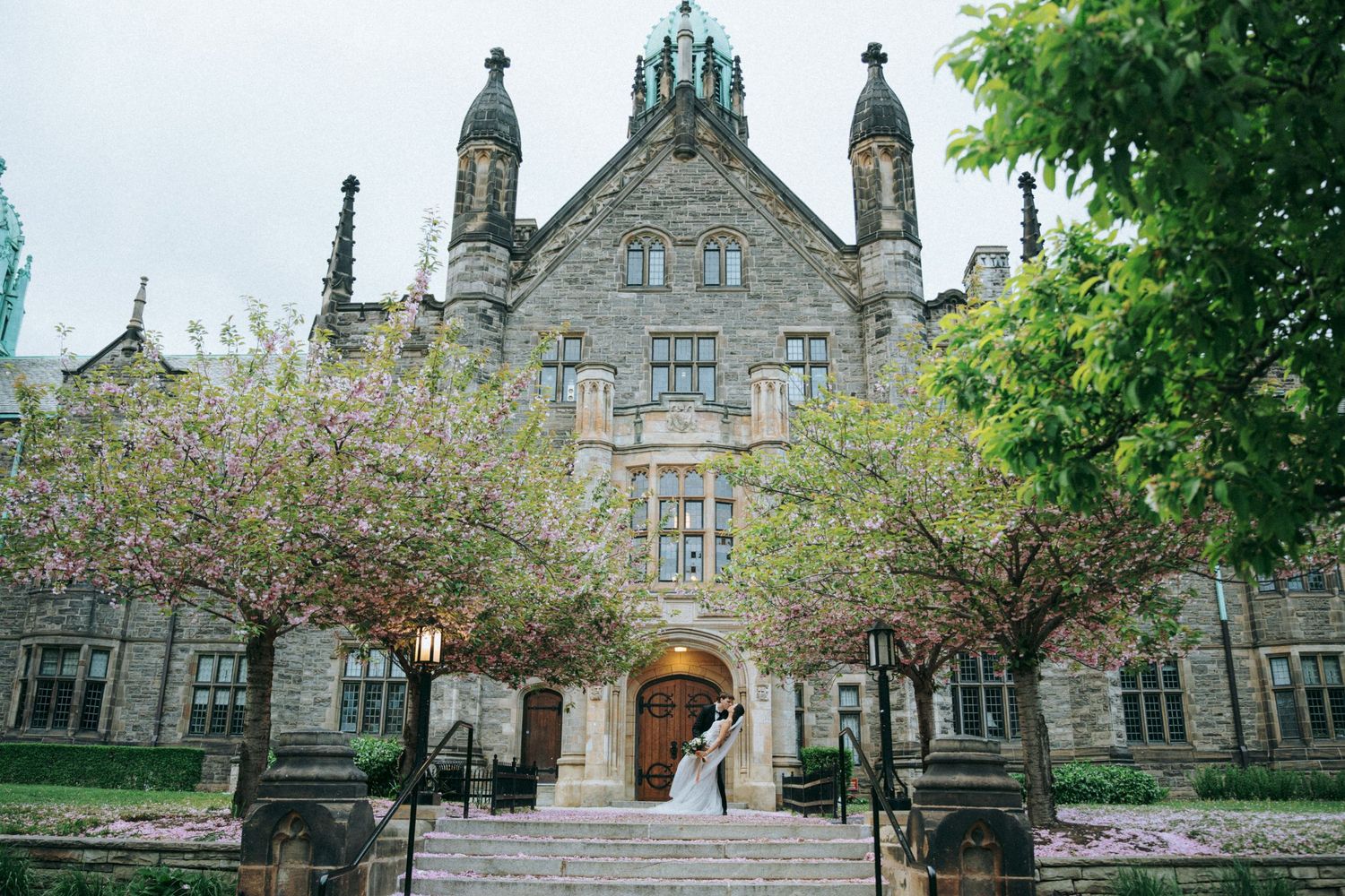Gothic stone church building with copper spires and blooming trees framing the grand entrance.