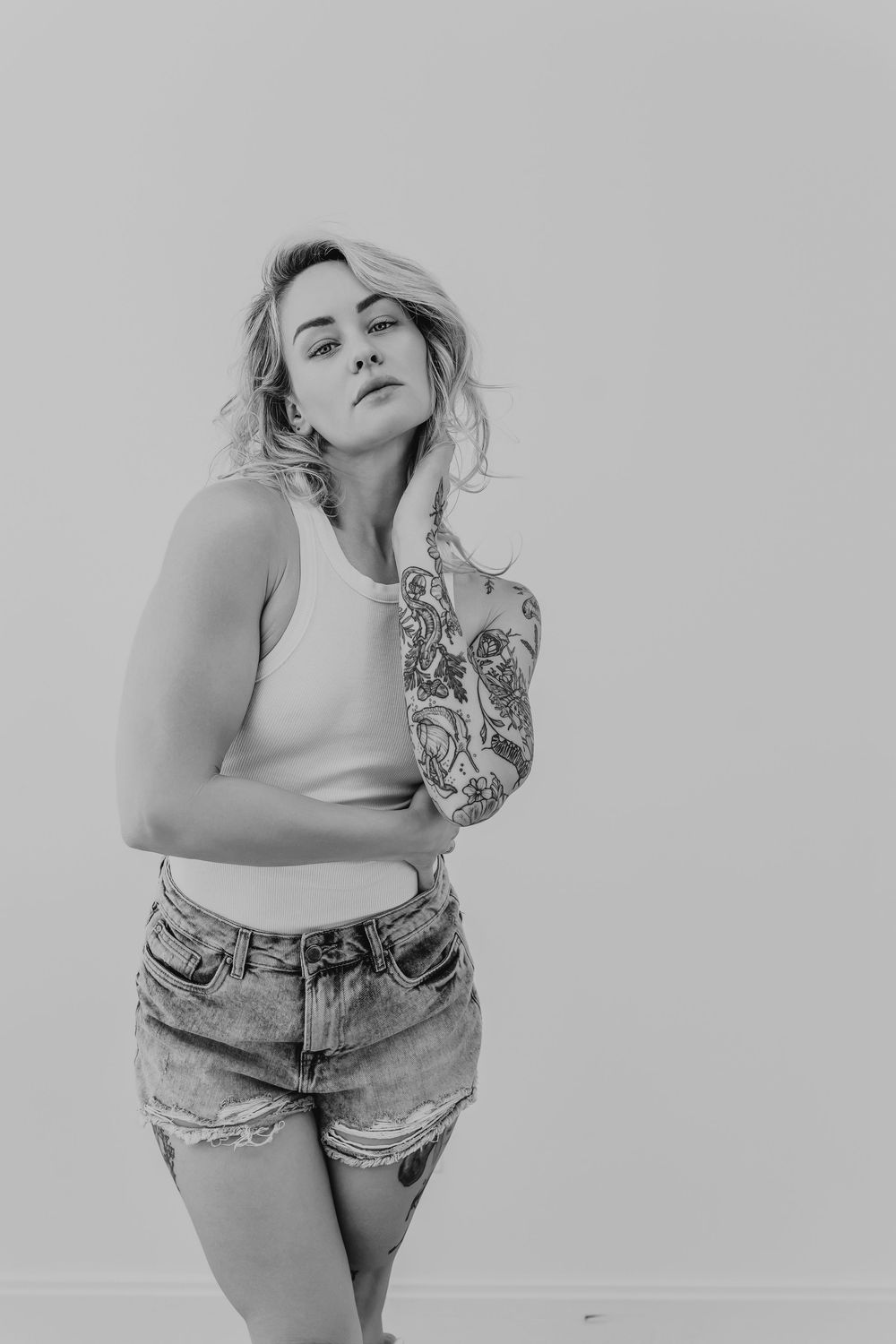 Black and white portrait of model posing in casual denim and tank top.