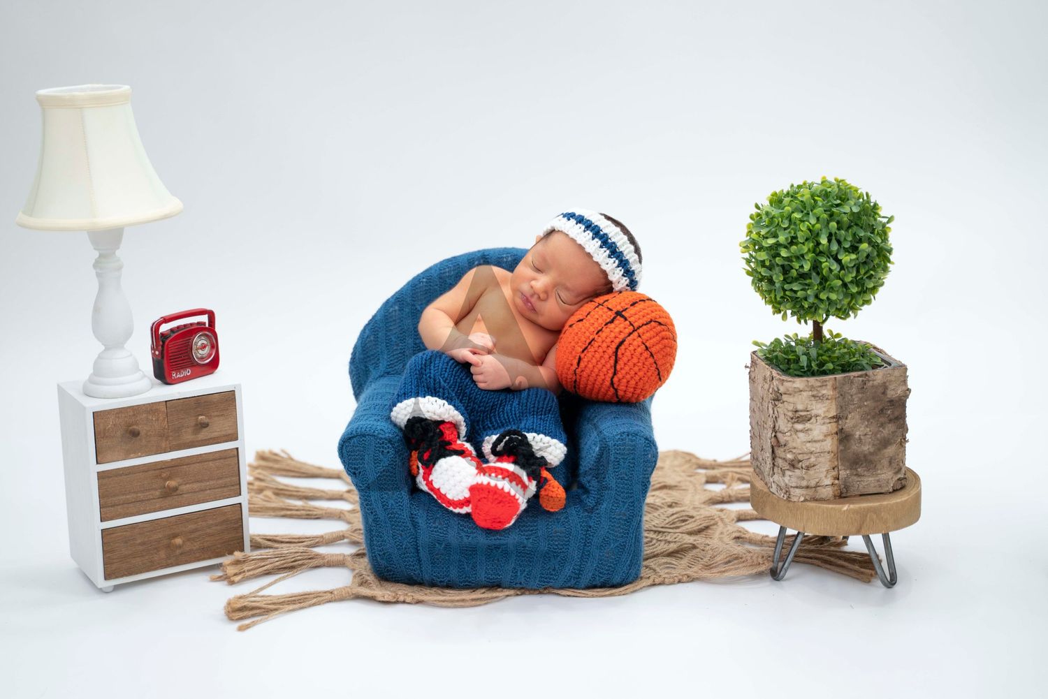 Cozy photography scene with blue armchair, basketball, side table and decorative plant.