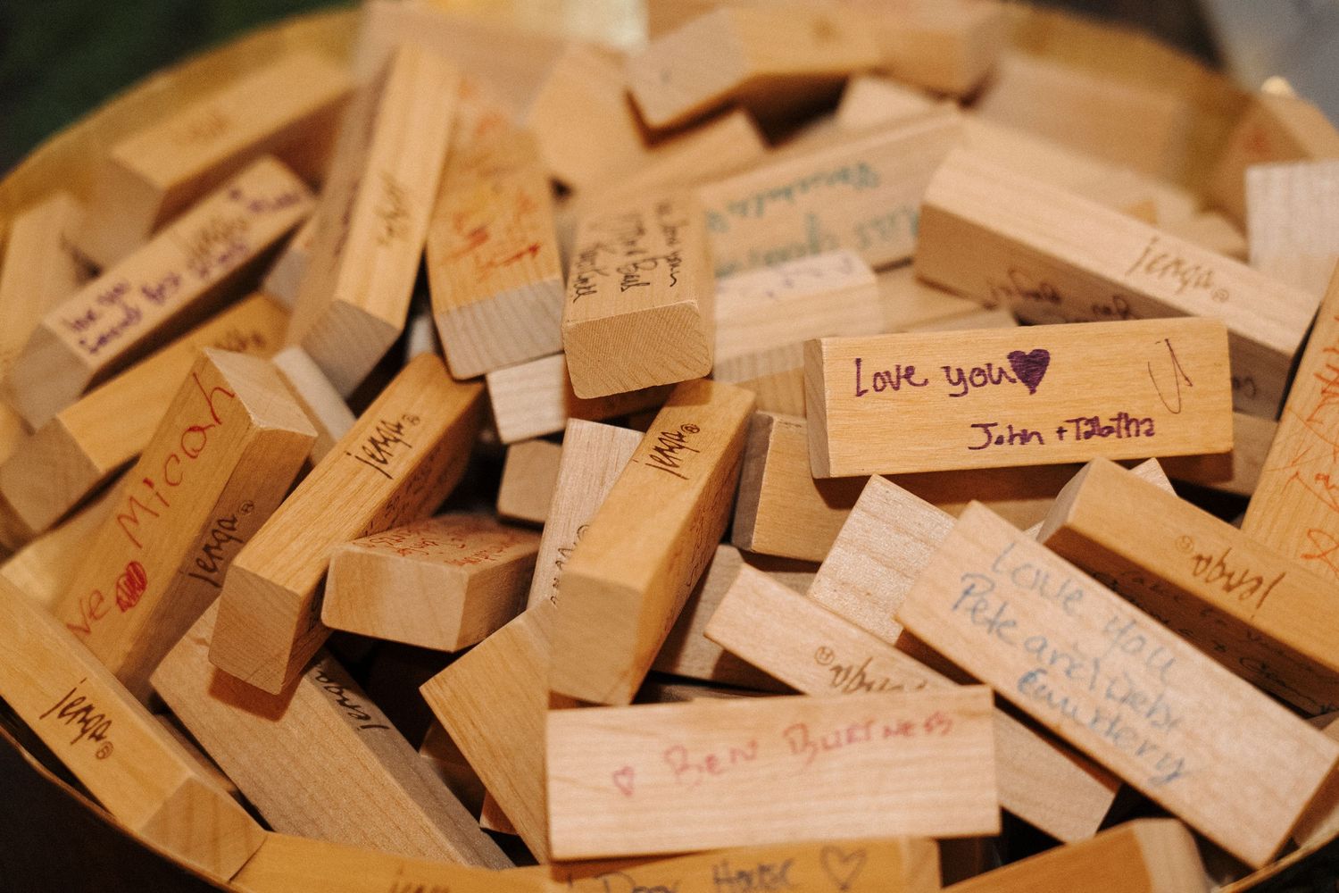 A collection of handwritten wooden name tags or labels scattered in a shallow wooden bowl.