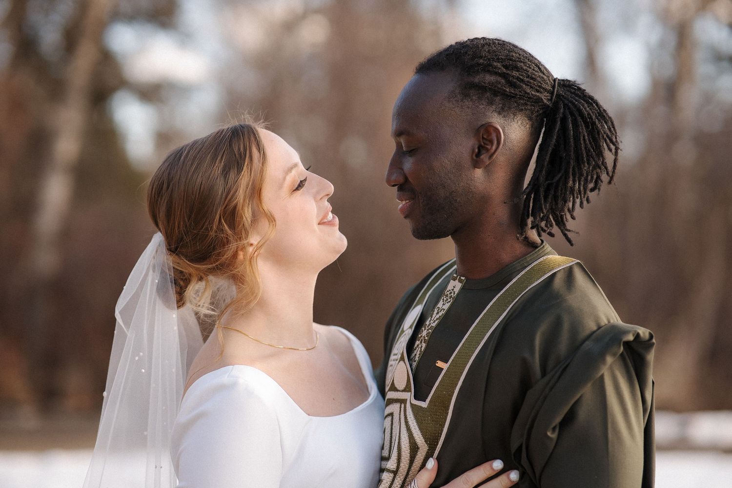 A bridal couple shares a tender moment together outdoors during an autumn wedding photoshoot.