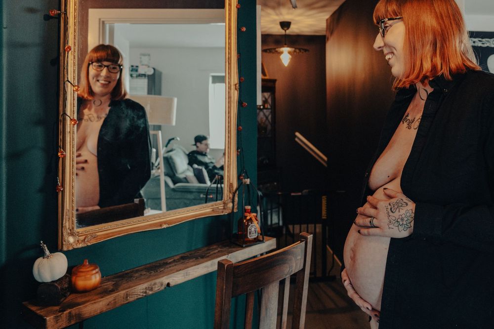 Lizzie and her bump during her at-home maternity session in Capel St Mary smiling in front of a mirror, colour, natural light