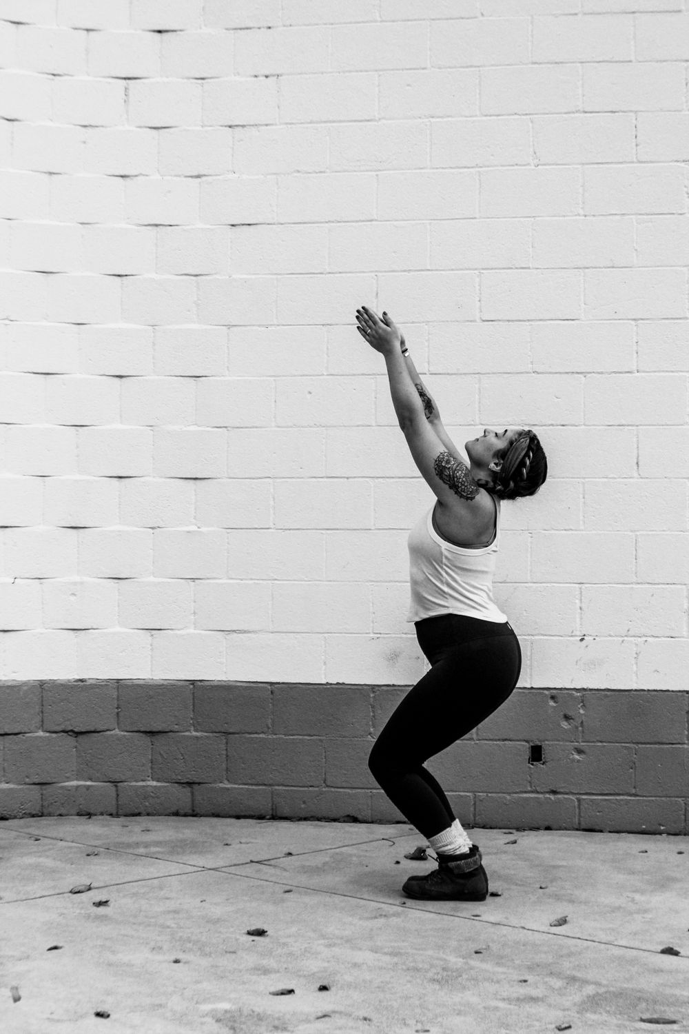 Dynamic dance movements captured in black and white against white brick wall.