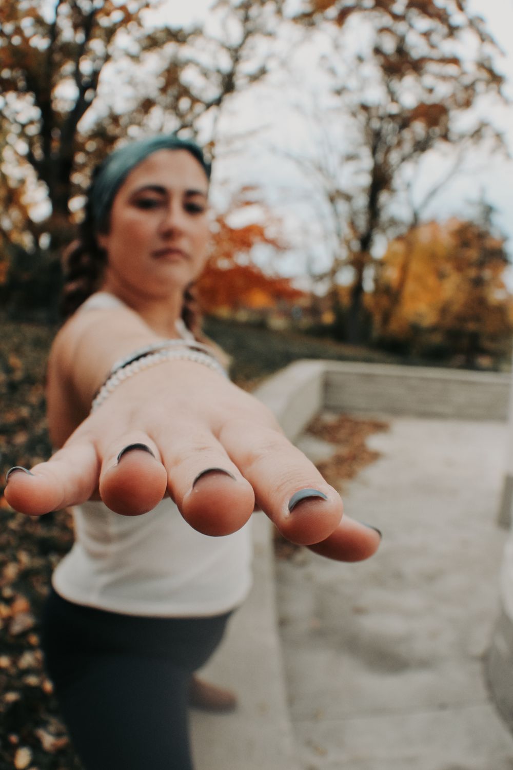 Hand reaching forward against autumn background with blurred trees.