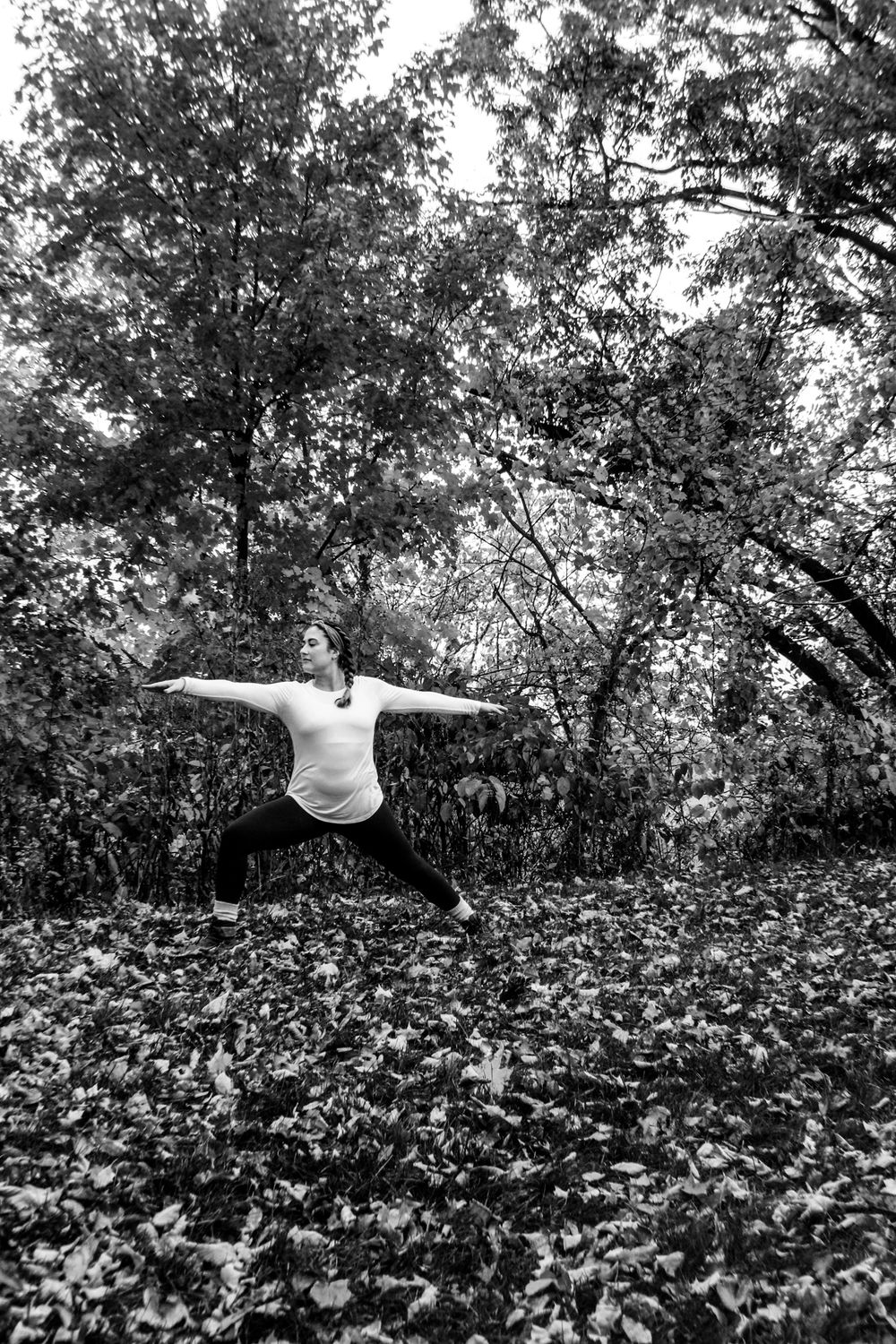 Black and white photo of figure among trees in natural setting.