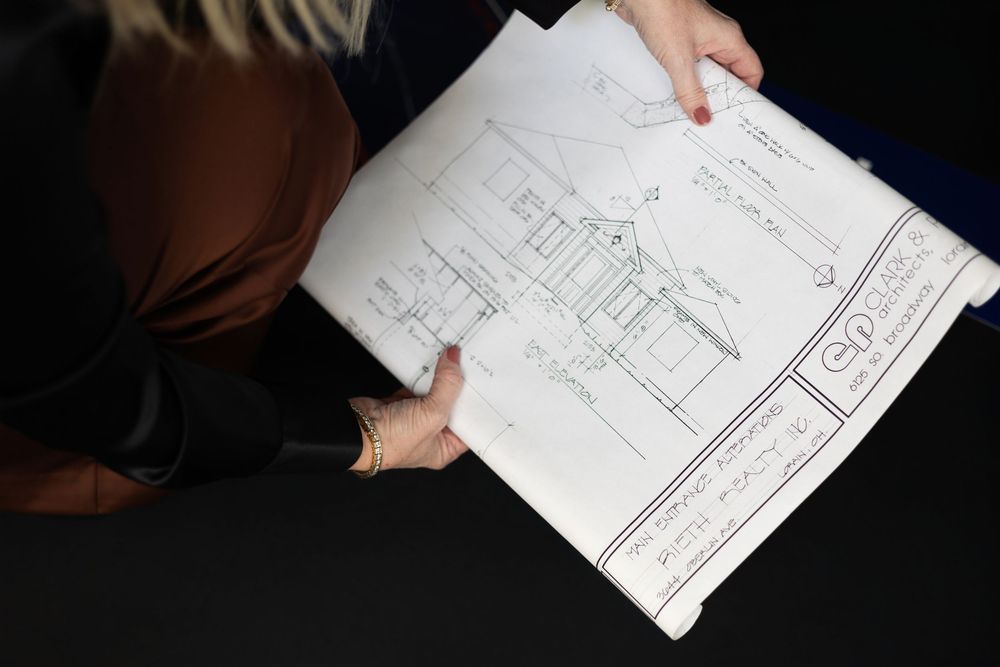 Hands holding business documents or architectural blueprints in a dark setting.