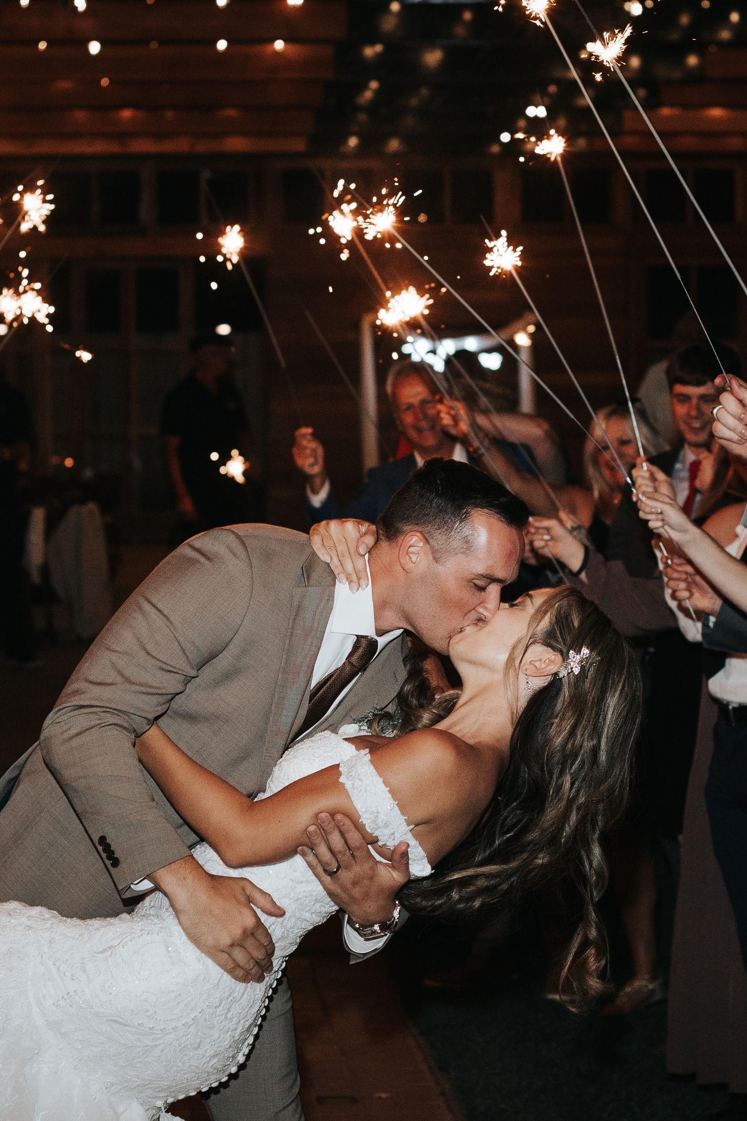 A newlywed couple sharing a romantic kiss during their sparkler exit at an indoor wedding reception celebration. Knoxville Photographer