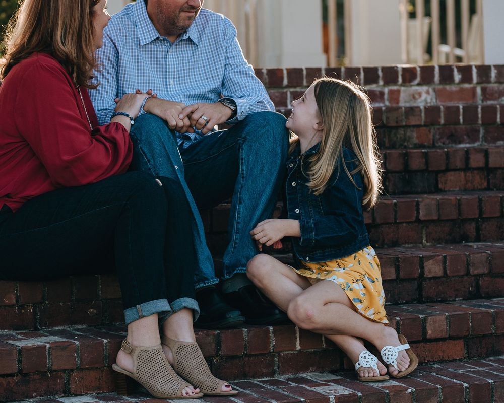 A child sits on brick steps with adults during a casual outdoor conversation.