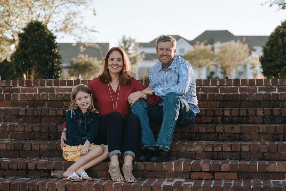 A family sits together on brick steps outdoors during a casual portrait session.
